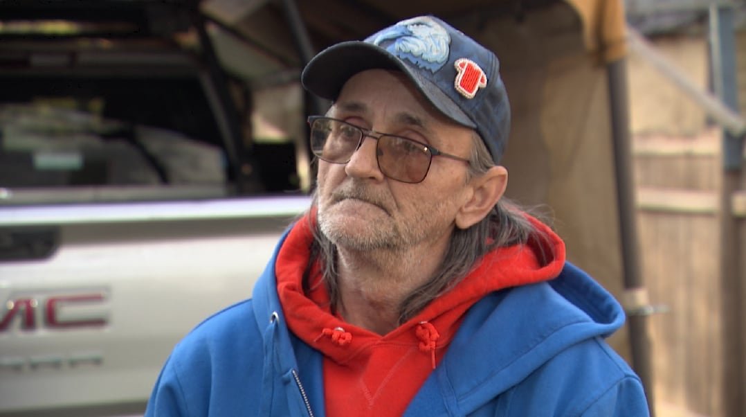 A man in a baseball cap looks forward.